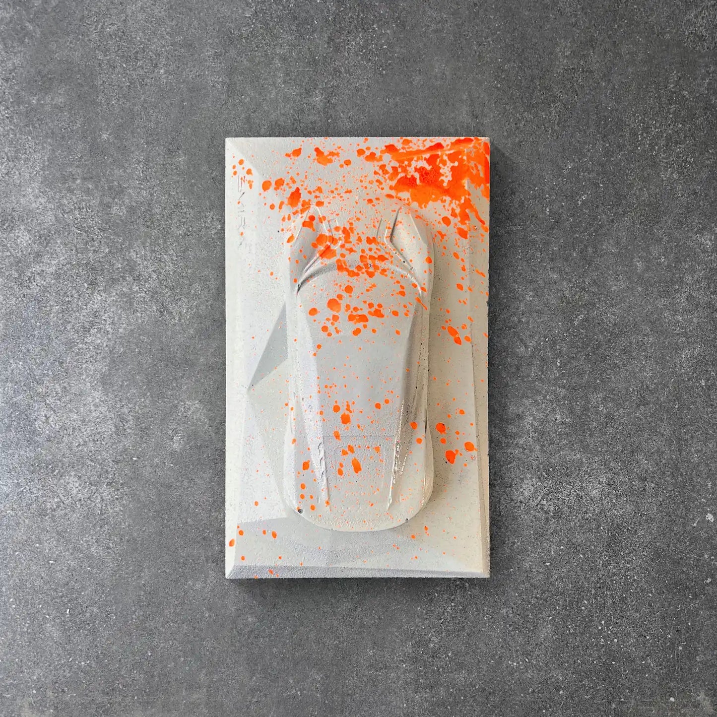 Lotus Emira concrete sculpture in grey with neon orange paint splatter street art style by CarArt Dubai