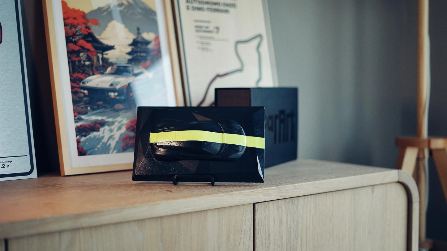 Lotus Emira concrete sculpture in black with neon yellow racing stripe, landscape mockup – CarArt Dubai