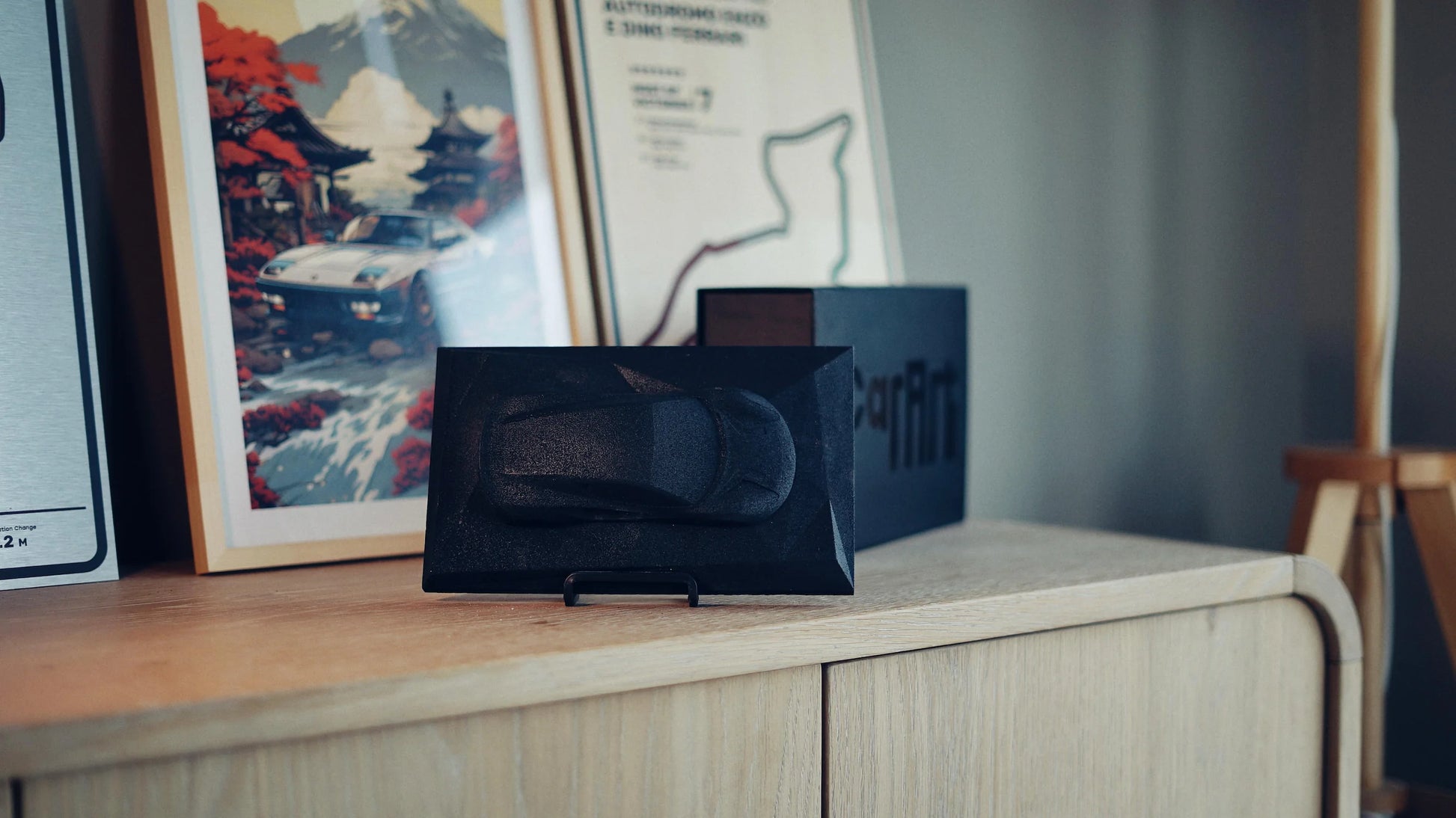 Lotus Emira concrete sculpture art mockup in deep black minimal finish, landscape display by CarArt Dubai