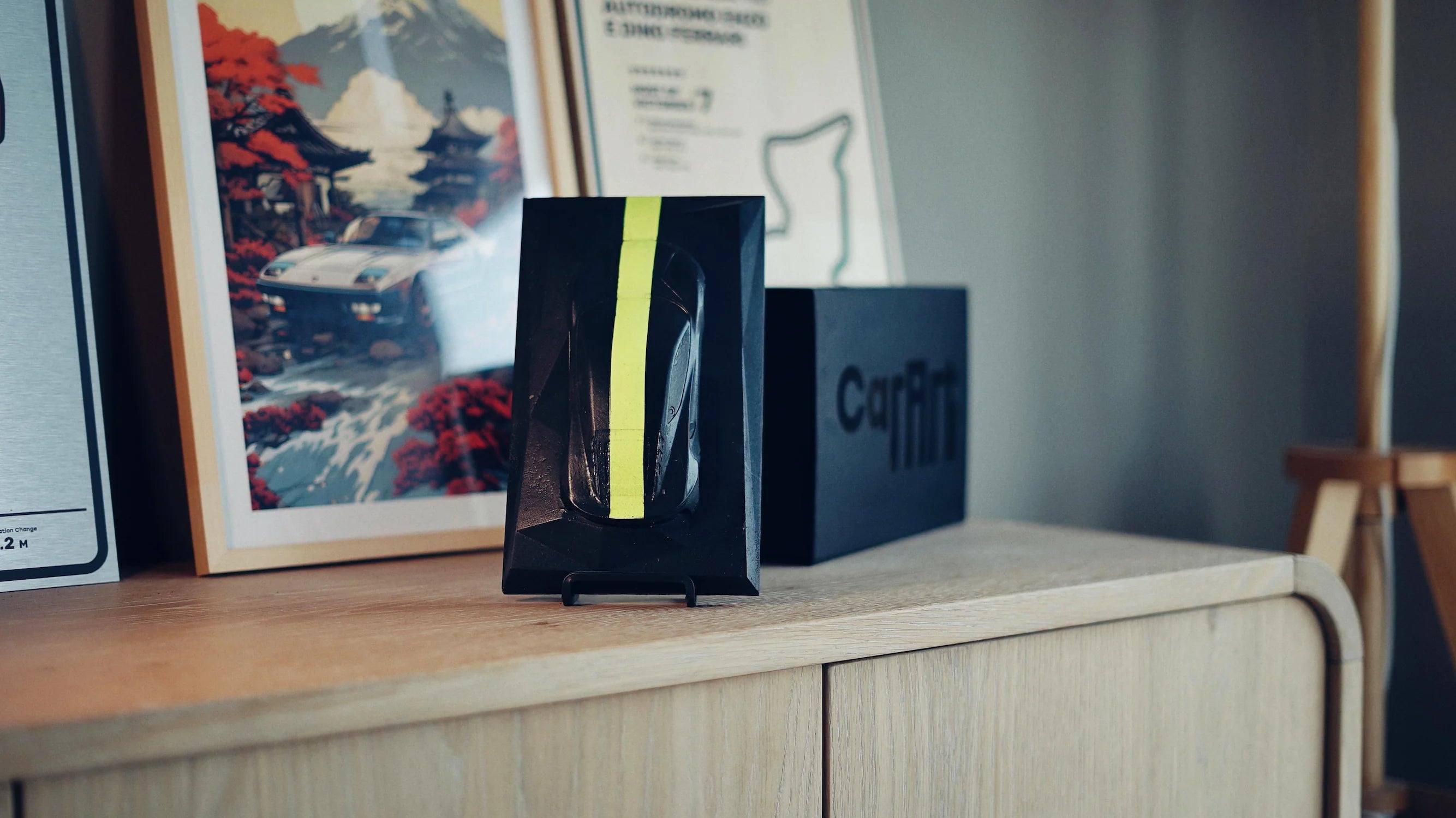 Lotus Emira concrete sculpture in black with neon yellow racing stripe, portrait mockup – CarArt Dubai